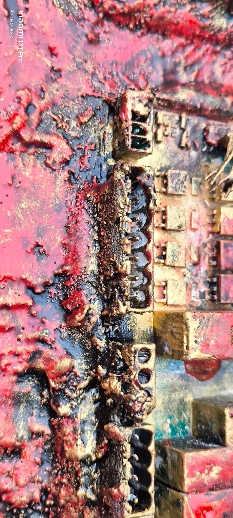 Détail en vue latérale : Composants électroniques en relief 3d. Recyclage éléments industriels de François Tapiézo. Textures, pigments rouges et dorés et matières sculptées.