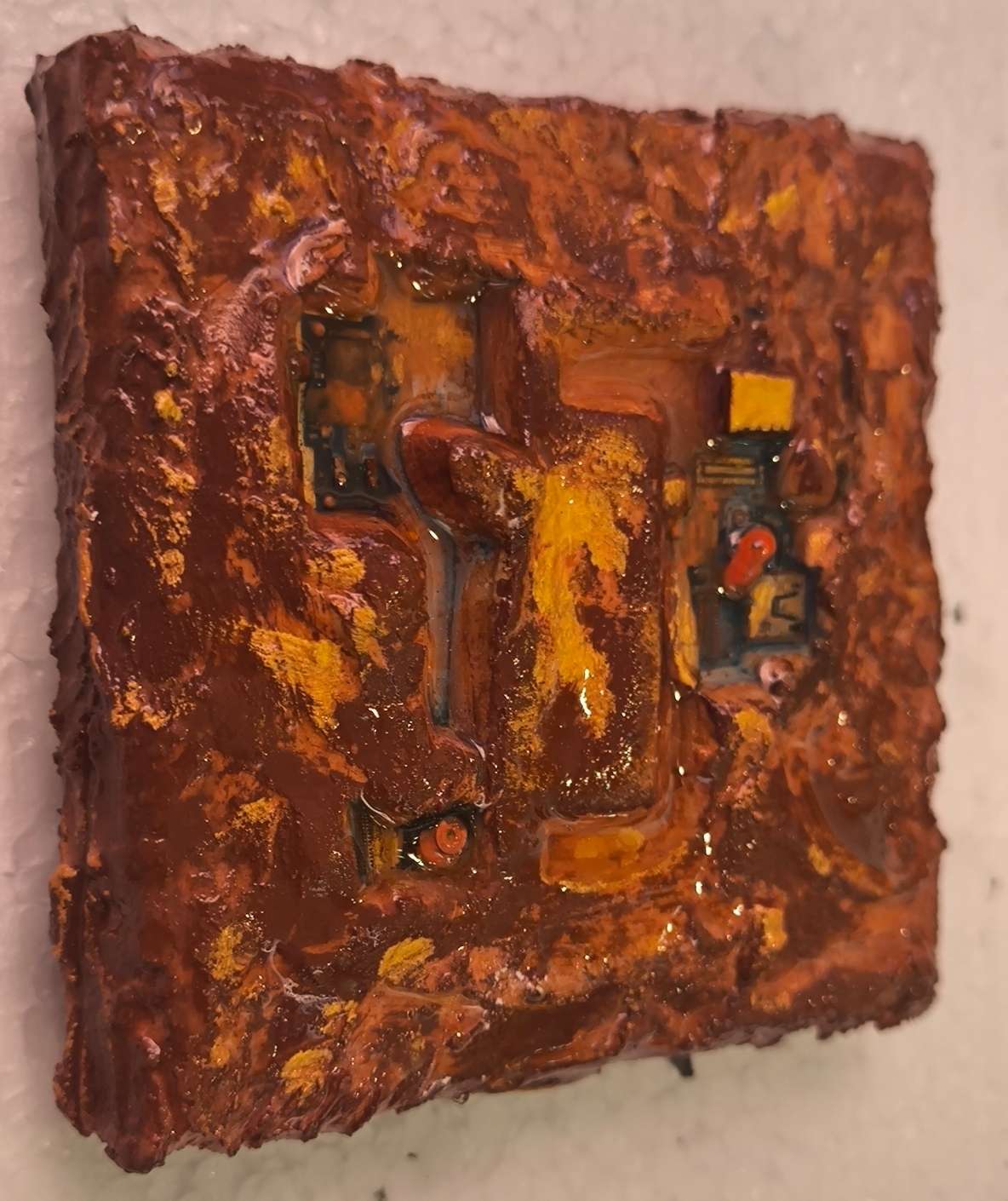Détails en vue latérale d'une carte cybernétique de téléphone intégré dans des matières de sables et pigments ocrés de Provence. Les textures sont rehausées d'or. Tableau contemporain unique en relief de François Tapiézo.
