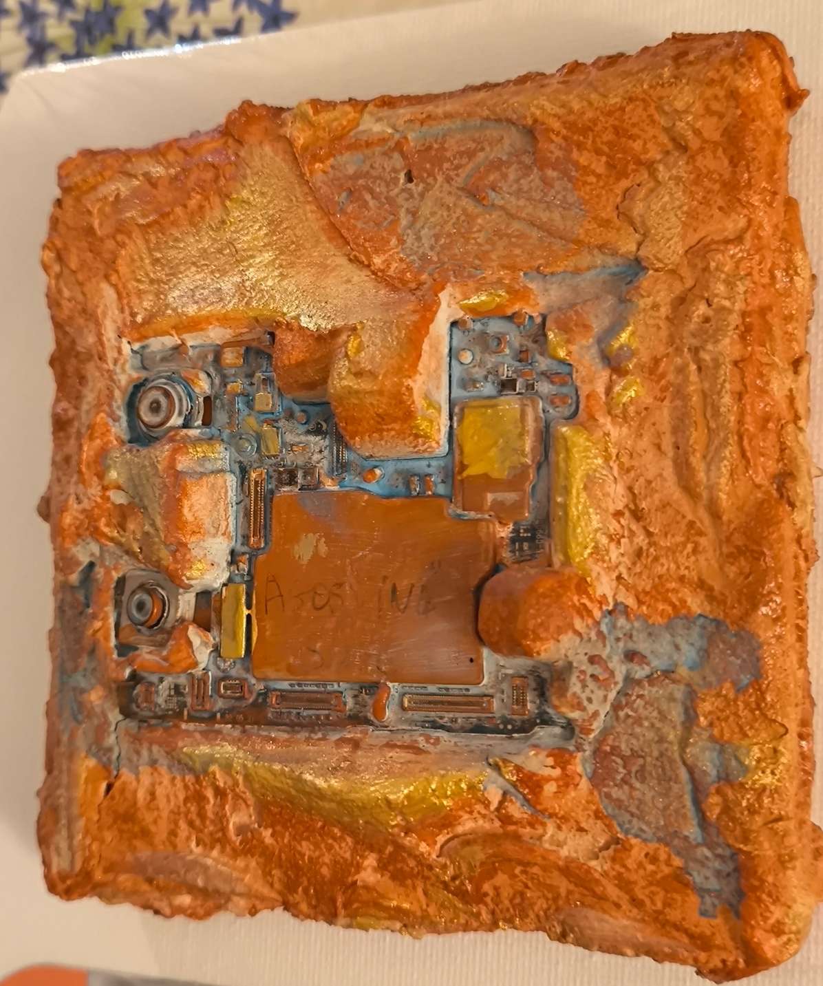 Détails en vue latérale de carte électronique de téléphone intégrée dans des textures de sables et pigments ocrés de Provence. Les matières sont rehausées d'or. Peinture contemporaine en relief de François Tapiézo.
