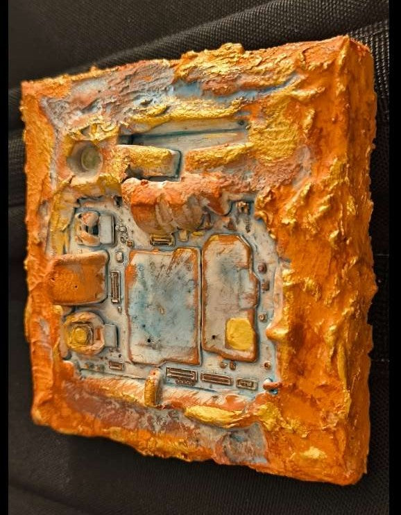 Vue latérale d'une carte électronique de téléphone portable recyclée dans des textures chaleureuses. Matières de sables et pigments de Provence. L'art relief de François Tapiézo.