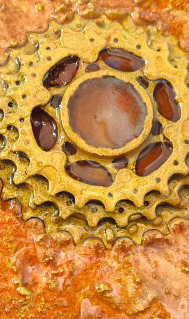 Détails en vue de face des roues dentées de la cassette de vélo immergée dans une texture ocrée, sous une résine brillante.  Peinture de François Tapiézo