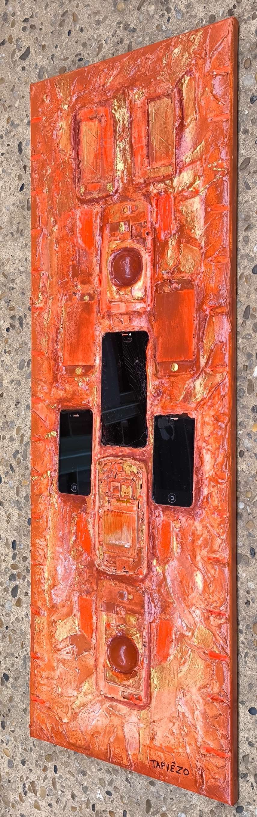 Détails en vue latérale de téléphones mobiles intégrés dans la matière. Technologie recyclée dans les sables et pigments de Roussillon par François Tapiézo. Création artistique sublimant l'obsolescence industrielle.